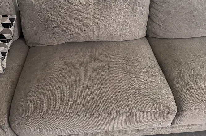 Spill stains soaked into a couch seat cushion before upholstery steam cleaning in Adelaide